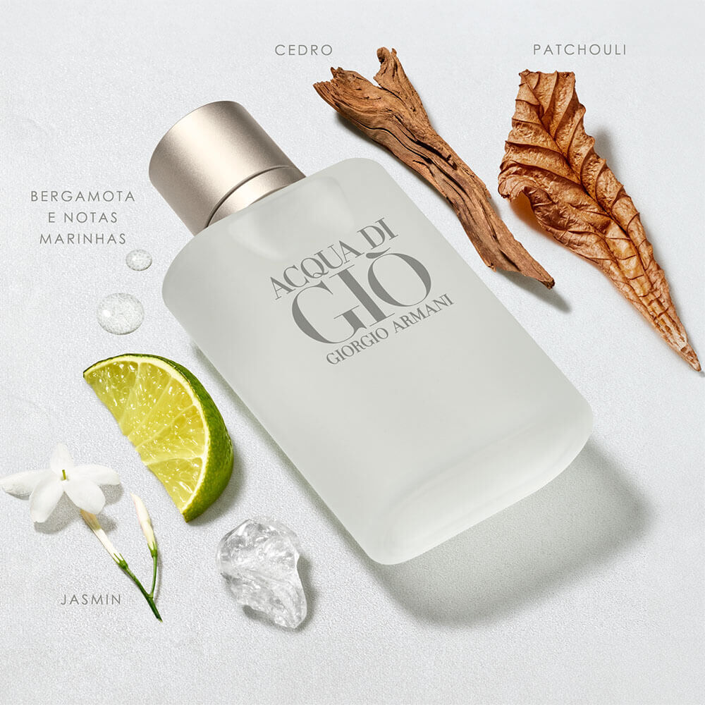 Cena Acqua di Giò: frasco fosco rodeado das matérias-primas — fatia de limão fresco, flor de jasmim, cristal de sal, pedaços de cedro e folha de patchouli sobre fundo claro