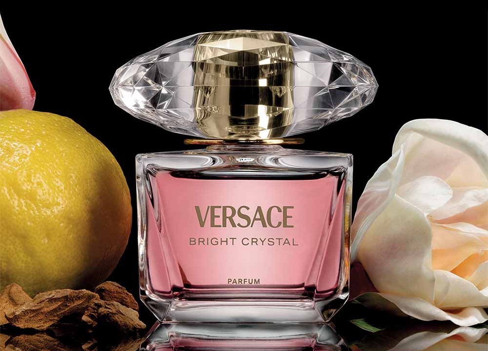Versace Bright Crystal Parfum 30ml emoldurado por yuzu, peônia e mogno sobre fundo preto — composição oficial Versace Beauty.