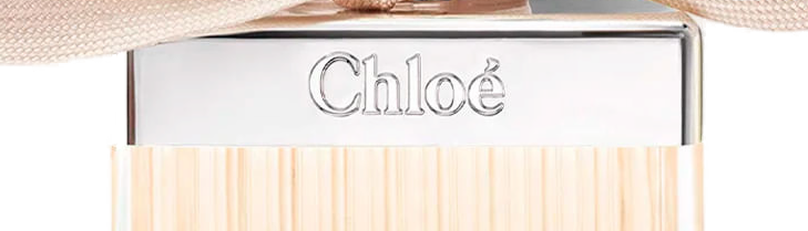 Close-up da placa cromada com Chloé gravado em serifa sobre o vidro canelado