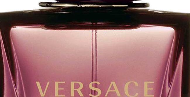 Close-up do VERSACE CRYSTAL NOIR em dourado sobre o vidro mauve translúcido facetado