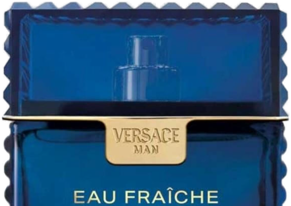 Close-up da placa dourada gravada VERSACE MAN sobre o vidro azul cobalto do Eau Fraîche Extreme