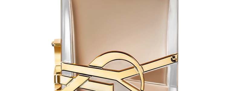 Close-up do monograma YSL em metal dourado aplicado lateralmente no frasco