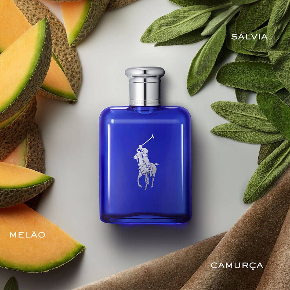 Cena Polo Blue: frasco cobalto sobre superfície clara, com fatias de melão à esquerda, folhas de sálvia esclareia à direita e tecido de camurça ao fundo