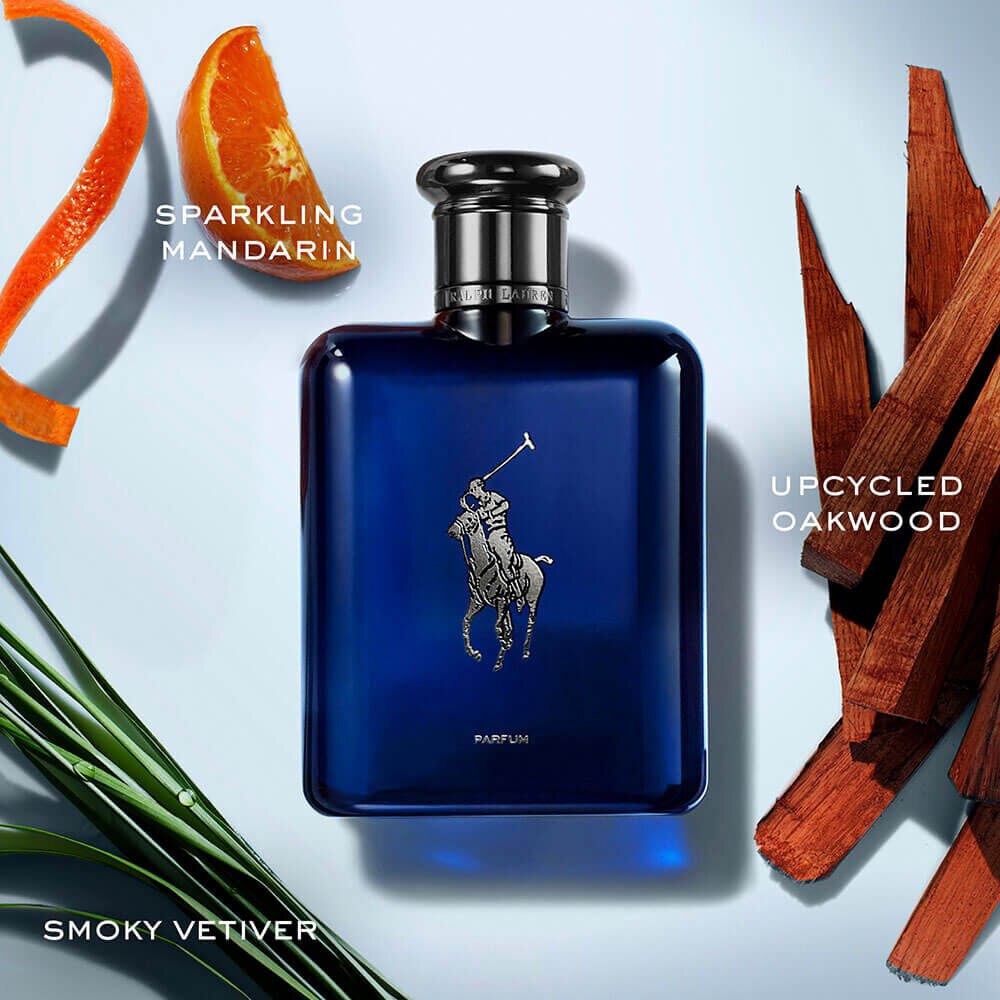 Cena Polo Blue Parfum: frasco safira escuro ao centro, casca de mandarim à esquerda, vetiver verde abaixo e lascas de madeira de carvalho à direita