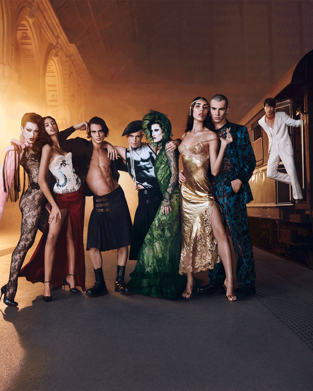 O elenco da campanha Scandal Express na plataforma do Le Majestic: alfaiataria couture Jean Paul Gaultier, vestidos de renda, smokings dourados — todos passageiros de primeira classe do escândalo.